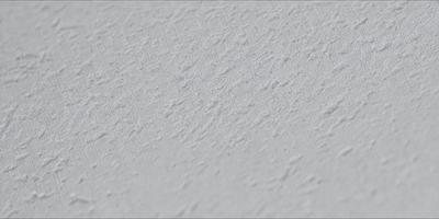 The primary subject of the image is a white wall with a pattern of white and gray stripes. The setting is a room with a white surface, and the visual style is a close-up of the wall. The colors and mood of the image are predominantly white and gray, creating a clean and minimalist atmosphere.