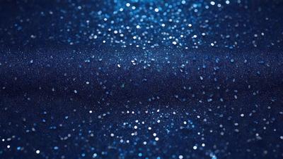 The primary subject of the image is a blue background with a pattern of glittering stars. The setting appears to be a dark room, and the visual style is a close-up of the blue background with the stars. The colors and mood of the image are predominantly dark and mysterious, with the blue background and the glittering stars creating a captivating and intriguing atmosphere.