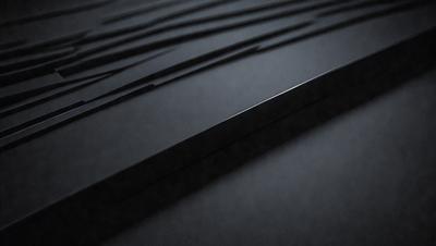 The primary subject of the image is a black metal surface, which appears to be a piece of metal or a metal sheet. The setting is a dark room, and the visual style is a close-up of the metal surface. The colors and mood of the image are predominantly dark and moody, with the black metal surface being the main focus.