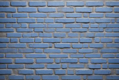 The primary subject of the image is a blue brick wall. The setting is a brick wall with a blue color, and the visual style is a photo. The colors and mood of the image are predominantly blue, creating a calm and serene atmosphere.