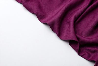 The primary subject of the image is a purple fabric, which is the main object, scene, or focus of the image. The setting is a white background, and the visual style is a photo. The colors and mood of the image are predominantly purple, creating a calm and serene atmosphere.