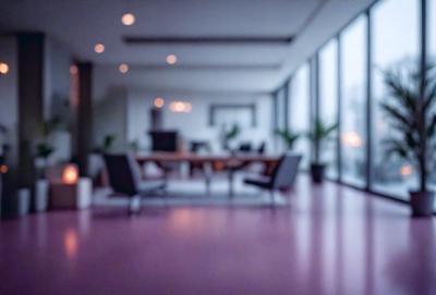 The primary subject of the image is a large room with a long table and several chairs. The room appears to be a conference room or a meeting space. The setting is a modern office environment, with a large window providing natural light. The visual style is a photo, capturing the room's interior in detail. The colors and mood of the room are predominantly neutral, with a focus on functionality and professionalism.