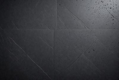 The primary subject of the image is a black tile wall. The setting is a dark room with a black tile floor. The visual style is a close-up of the tile wall, showcasing its texture and design. The colors and mood of the image are predominantly dark, with the black tile and floor creating a moody atmosphere.