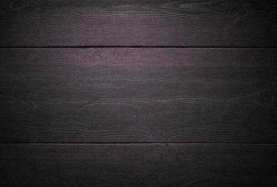 The primary subject of the image is a wooden floor. The setting is a dark room, and the visual style is a photo. The colors and mood of the image are dark and moody, with the wooden floor being the main focus.