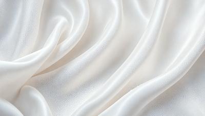 The primary subject of the image is a white fabric, possibly a sheet or a curtain, with a pattern of white dots. The setting is a white background, which creates a clean and minimalist appearance. The visual style is a close-up of the fabric, showcasing its texture and pattern. The colors and mood of the image are predominantly white, giving it a calm and serene atmosphere.