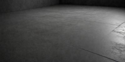 The primary subject of the image is a large, empty room with a concrete floor. The setting is a dark room, possibly a basement, with a concrete surface. The visual style is a black and white photo, giving the image a classic and timeless appearance. The colors and mood of the image are predominantly dark and moody, with the concrete floor and walls creating a stark and minimalist atmosphere.