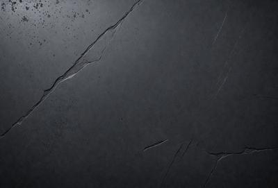 The primary subject of the image is a black surface, possibly a wall or a piece of artwork. The setting is a dark room, and the visual style appears to be a close-up of the black surface. The colors and mood of the image are predominantly dark and moody, with the black surface being the main focus.