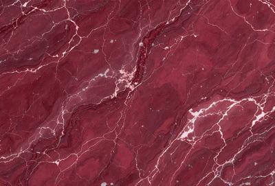 The primary subject of the image is a close-up of a marbled surface, which appears to be a red and brown stone. The setting is a wall with a patterned texture, giving the impression of a natural stone wall. The visual style is a close-up of the marbled surface, showcasing the intricate patterns and textures. The colors and mood of the image are predominantly red and brown, creating a warm and earthy atmosphere.
