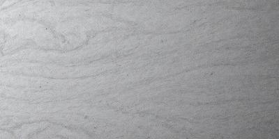 The image features a large, gray marble surface with a pattern of swirls and waves. The setting appears to be a stone or marble countertop, possibly in a kitchen or bathroom. The visual style is a close-up of the marble surface, showcasing its unique texture and pattern. The colors in the image are predominantly gray, giving the scene a calm and sophisticated atmosphere.