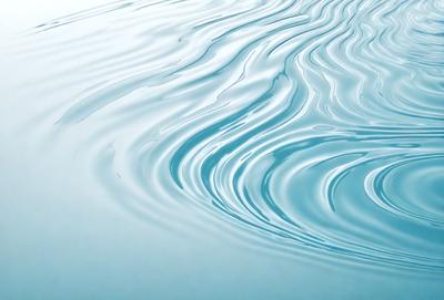 The primary subject of the image is a body of water, which appears to be a large lake or a large pool. The water is blue and has a rippling effect, giving it a dynamic and flowing appearance. The setting is a calm and serene environment, with no visible disturbances or objects in the background. The visual style of the image is a close-up of the water, emphasizing its texture and movement. The colors and mood of the image are predominantly blue, creating a sense of tranquility
