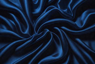 The primary subject of the image is a blue fabric, which appears to be a piece of cloth or a curtain. The setting is a dark room, and the visual style is a close-up of the blue fabric. The colors and mood of the image are predominantly dark and moody, with the blue fabric being the main focus.