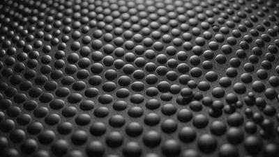 The primary subject of the image is a close-up of a black and white patterned surface, which appears to be a textured material. The setting is a black background, and the visual style is a close-up of the pattern. The colors and mood of the image are predominantly black and white, giving it a classic and timeless appearance.
