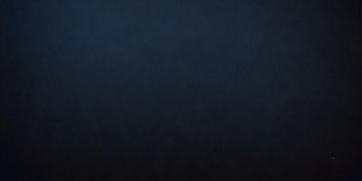 The primary subject of the image is a dark blue background. The setting is a black background, which creates a dramatic and moody atmosphere. The visual style is a close-up of the dark blue background, emphasizing its richness and depth. The colors and mood of the image are predominantly dark and mysterious, with the blue hue adding a sense of calmness and tranquility.