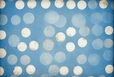 The primary subject of the image is a blue background with white polka dots. The setting is a wall, and the visual style is a pattern. The dominant colors are blue and white, creating a calm and soothing atmosphere.