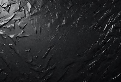 The primary subject of the image is a black background with a pattern of white lines. The setting appears to be a dark room, and the visual style is a combination of a photo and a digital artwork. The dominant colors are black and white, creating a moody atmosphere.