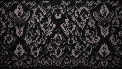 The primary subject of the image is a black and white lace pattern. The setting is a black background, which contrasts with the lace pattern. The visual style is a close-up of the lace pattern, showcasing its intricate details. The colors and mood of the image are predominantly dark and moody, with the black and white lace pattern creating a striking contrast against the black background.