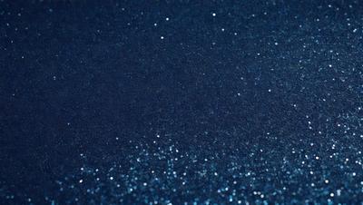 The primary subject of the image is a blue background with a pattern of glittering stars. The setting appears to be a dark room, and the visual style is a close-up of the blue background with the stars. The colors and mood of the image are predominantly dark and mysterious, with the blue background and the glittering stars creating a captivating and intriguing atmosphere.