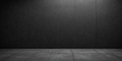 The primary subject of the image is a large, dark grey wall. The setting is a room with a concrete floor. The visual style is a black and white photo. The dominant colors are grey, and the overall atmosphere is moody and dramatic.