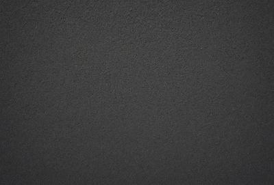 The primary subject of the image is a black surface, which appears to be a wall or a piece of fabric. The setting is a dark room, and the visual style is a close-up of the black surface. The colors and mood of the image are predominantly dark and moody, with the black surface being the main focus.
