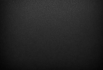 The primary subject of the image is a black background with a smooth, shiny surface. The setting is a dark room, and the visual style is a close-up of the black background. The colors and mood of the image are predominantly dark and moody, with the black background being the main focus.