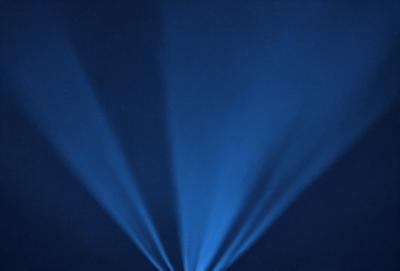 The primary subject of the image is a blue light, which appears to be a spotlight or a light source. The setting is a dark room, and the visual style is a digital art or illustration. The dominant colors in the image are blue and black, creating a moody atmosphere.