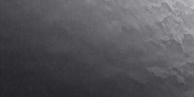 The primary subject of the image is a black background with a white dot. The setting is a dark, cloudy sky, and the visual style is a black and white photo. The colors and mood of the image are predominantly dark and moody, with the white dot being the only bright spot in the scene.