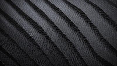 The primary subject of the image is a black cord with a patterned design. The setting is a dark background, which contrasts with the cord. The visual style is a close-up of the cord, showcasing its unique pattern. The colors and mood of the image are predominantly dark, with the black cord being the main focus.