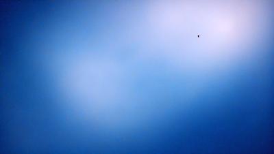 The primary subject of the image is the sky, which is a deep blue color. The setting is a cloudy day, with a few clouds visible in the sky. The visual style of the image is a photo, capturing the beauty of the cloudy sky. The colors and mood of the image are serene and peaceful, as the sky is void of any disturbances or objects.