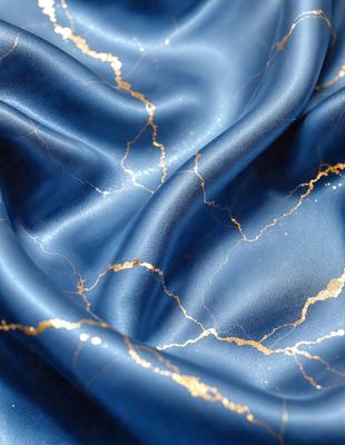 The primary subject of the image is a blue fabric with gold speckles. The setting is a close-up view of the fabric, showcasing its unique pattern. The visual style is a detailed, up-close representation of the fabric. The dominant colors are blue and gold, creating a rich and luxurious atmosphere.