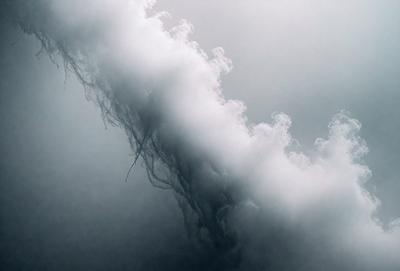 The primary subject of the image is a cloudy sky with a large, curling cloud. The setting is a dark, cloudy day, and the visual style is a photo. The dominant colors are grays and blues, creating a moody atmosphere.
