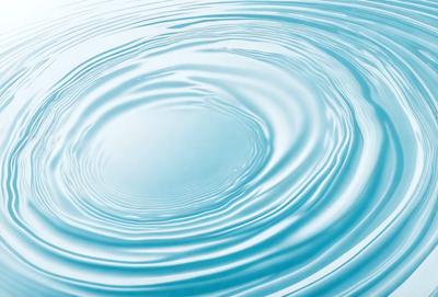 The primary subject of the image is a large, blue, rippling wave. The wave is the main focus of the image, and it appears to be a natural, water-based phenomenon. The setting is a body of water, and the visual style is a close-up of the wave, showcasing its texture and movement. The colors and mood of the image are predominantly blue, which gives the scene a calm and serene atmosphere.