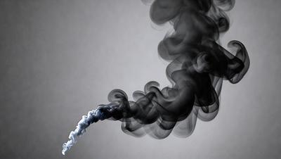 The primary subject of the image is a smoke trail, which appears to be a drawing or illustration. The setting is a gray background, which complements the smoke trail. The visual style is artistic, and the colors and mood are dark and moody.