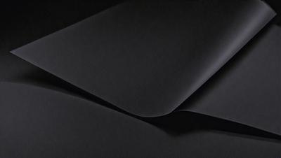 The primary subject of the image is a black cloth, which is the main object, scene, or focus of the image. The setting or background is a dark room, and the visual style is a close-up of the black cloth. The colors and mood of the image are predominantly dark and moody, with the black cloth being the dominant color.