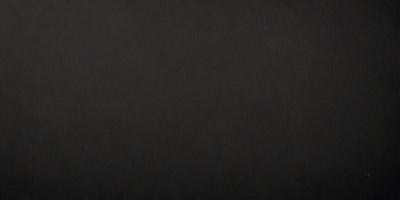 The primary subject of the image is a black leather surface. The setting is a dark room, and the visual style is a close-up of the leather surface. The colors and mood of the image are predominantly dark and moody, with the black leather surface being the main focus.