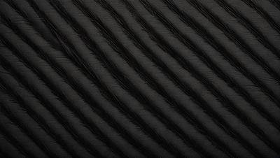 The primary subject of the image is a black and white patterned surface, which appears to be a woven fabric or a textured wallpaper. The setting is a black background, which emphasizes the pattern and texture of the surface. The visual style is a close-up of the pattern, showcasing its intricate details. The colors and mood of the image are predominantly black and white, giving it a classic and timeless feel.