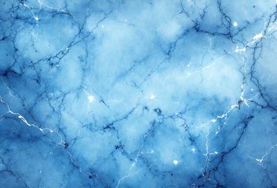 The primary subject of the image is a blue marble wall with a pattern of white streaks. The setting is a room with a blue marble wall, and the visual style is a photo. The dominant colors are blue and white, creating a calm and serene atmosphere.