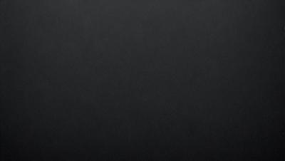 The primary subject of the image is a black background. The setting is a dark room, and the visual style is a black and white photo. The colors and mood of the image are dark and moody, creating a sense of mystery or drama.