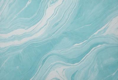 The primary subject of the image is a blue and white marbled tile. The setting is a bathroom, as the tile is placed on a wall. The visual style is a close-up of the tile, showcasing its intricate design. The dominant colors are blue and white, creating a calm and soothing atmosphere.