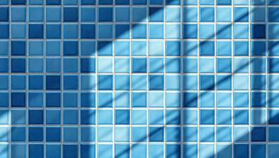 The primary subject of the image is a blue tile wall with a pattern of blue squares. The setting is a room with a blue tile floor. The visual style is a photo, and the dominant colors are blue and white. The overall atmosphere is bright and clean, with the blue tiles creating a sense of calm and order.