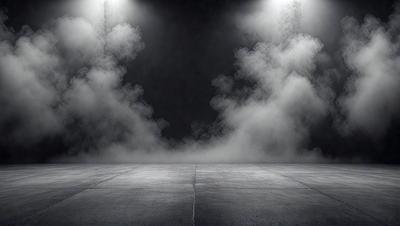 The primary subject of the image is a large, dark room with a concrete floor. The setting appears to be a stage or a performance area, as there is a large amount of smoke or fog filling the room. The visual style of the image is a black and white photo, which adds a dramatic and artistic touch to the scene. The colors and mood of the image are dark and moody, creating a sense of mystery and intensity.