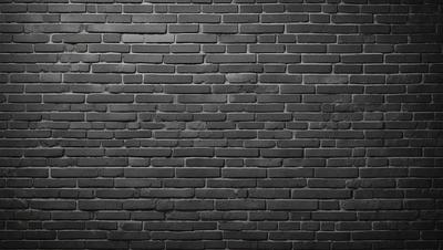 The primary subject of the image is a brick wall. The setting is a dark room, and the visual style is a black and white photo. The dominant colors are black and white, creating a moody atmosphere.