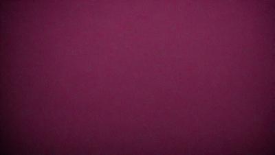 The primary subject of the image is a large, dark red surface. The setting appears to be a dark room, with the red surface being the main focus. The visual style of the image is a close-up of the red surface, which gives it a dramatic and intense appearance. The colors and mood of the image are dominated by the deep red hue, creating a sense of mystery and intensity.
