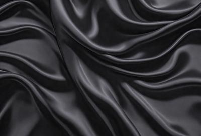 The primary subject of the image is a black fabric, which appears to be a piece of clothing or a curtain. The setting is a dark room, and the visual style is a close-up of the fabric. The colors and mood of the image are predominantly dark and moody, with the black fabric being the main focus.