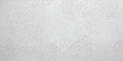 The primary subject of the image is a white wall with a rough texture. The setting is a room with a plain, unadorned appearance. The visual style is a close-up of the wall, showcasing its texture and surface. The colors and mood of the image are predominantly white, giving it a clean and minimalist feel.