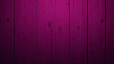 The primary subject of the image is a wooden wall with a purple color. The setting is a room with a wooden floor. The visual style is a close-up of the wooden wall, showcasing its texture and color. The dominant colors are purple and brown, creating a warm and cozy atmosphere.