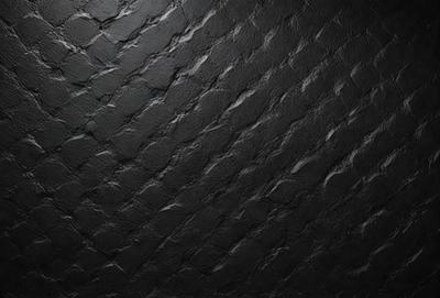 The primary subject of the image is a black and white patterned wall. The setting is a dark room, and the visual style is a close-up of the wall. The dominant colors are black and white, creating a moody atmosphere.