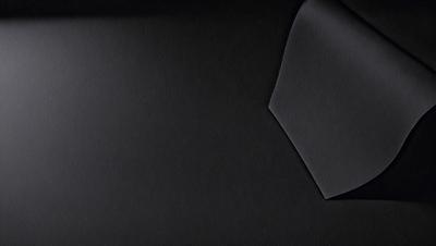 The primary subject of the image is a black cloth, which is the main object, scene, or focus of the image. The setting or background is a dark surface, and the visual style appears to be a photo. The colors and mood of the image are predominantly dark and moody, with the black cloth being the most prominent element.