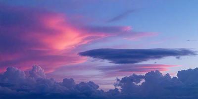 The primary subject of the image is a cloudy sky with a pink hue. The setting is a beautiful sunset, creating a serene and peaceful atmosphere. The visual style is a natural, outdoor scene, with no indication of being a photo, digital art, illustration, drawing, pattern, texture, or clipart. The colors and mood are predominantly pink and warm, with the clouds adding depth and texture to the sky.