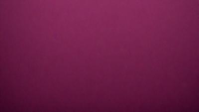 The primary subject of the image is a large, purple wall. The setting is a room with a pink background. The visual style is a close-up of the wall, which gives a sense of depth and texture. The dominant colors are purple and pink, creating a warm and inviting atmosphere.