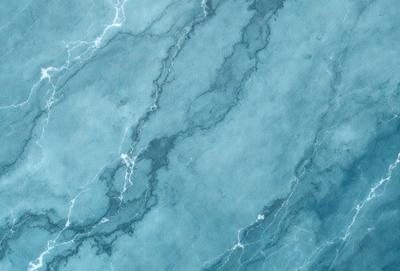The primary subject of the image is a blue marble wall with a pattern of white and blue swirls. The setting is a room with a blue marble floor, and the visual style is a close-up of the marble wall. The colors and mood of the image are predominantly blue, creating a calm and serene atmosphere.